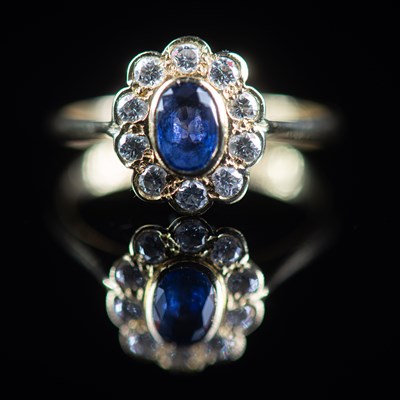 Lot 591 - AN 18 CARAT YELLOW GOLD SAPPHIRE AND DIAMOND OVAL CLUSTER RING