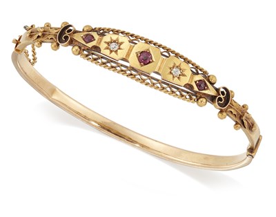 Lot 1597 - AN EDWARDIAN 15 CARAT GOLD RUBY AND DIAMOND HINGE OPENING BANGLE