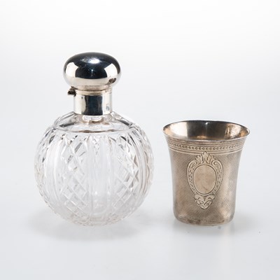 Lot 1069 - A FRENCH ENGINE-TURNED SILVER BEAKER AND A GEORGE V SILVER-TOPPED CUT-GLASS SCENT BOTTLE