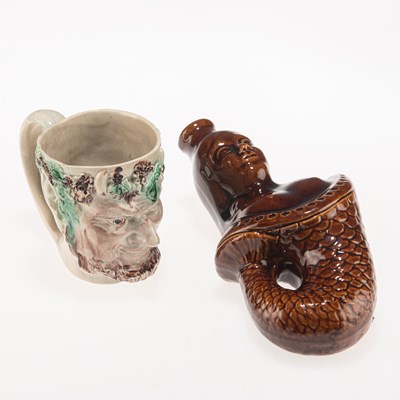 Lot 86 - AN EARLY 19TH CENTURY PEARLWARE BACCHUS MASK MUG, AND LATE 19TH CENTURY TREACLE-GLAZED SPIRIT FLASK